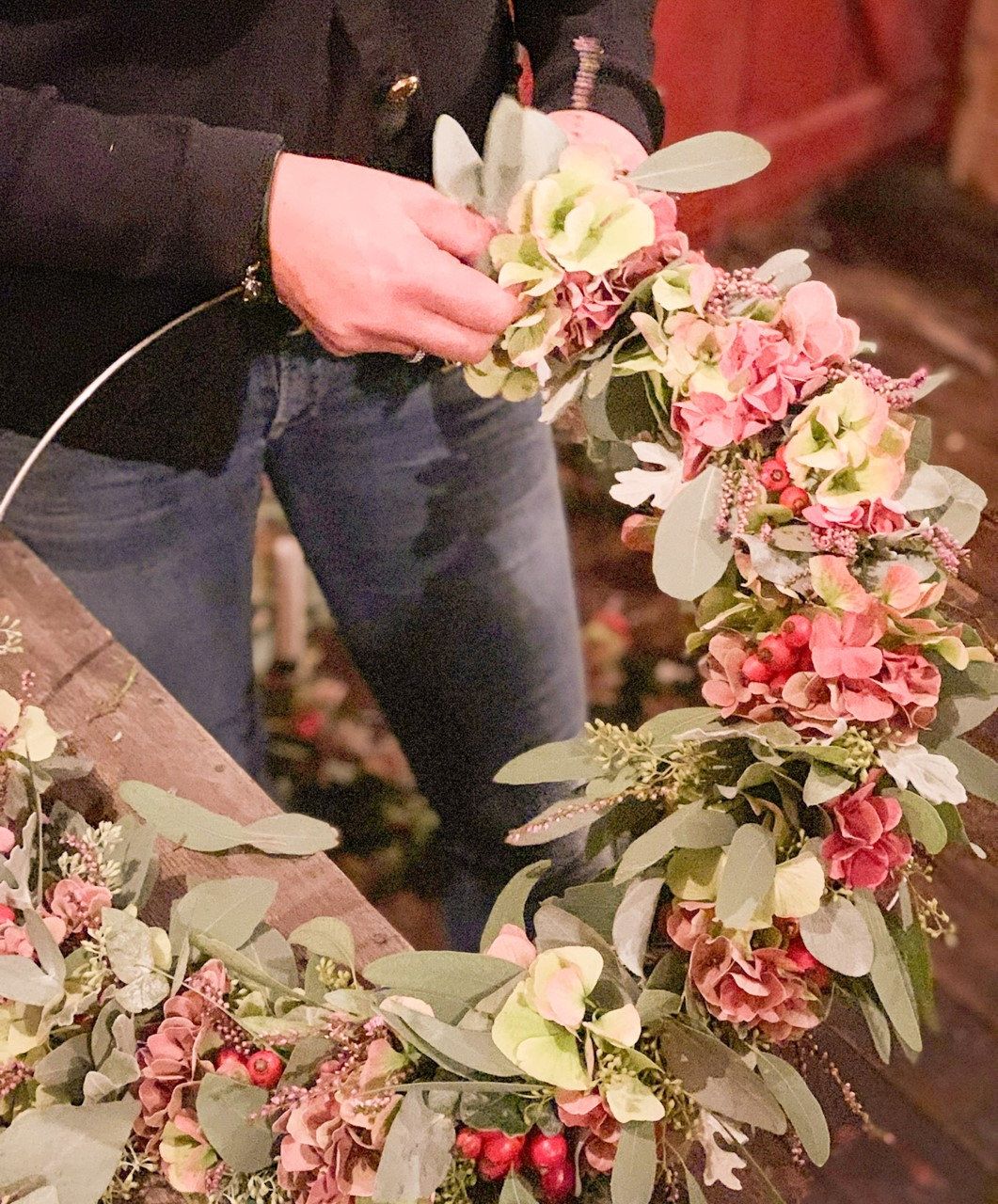 Händer som binder en krans av hortensia och eukalyptus